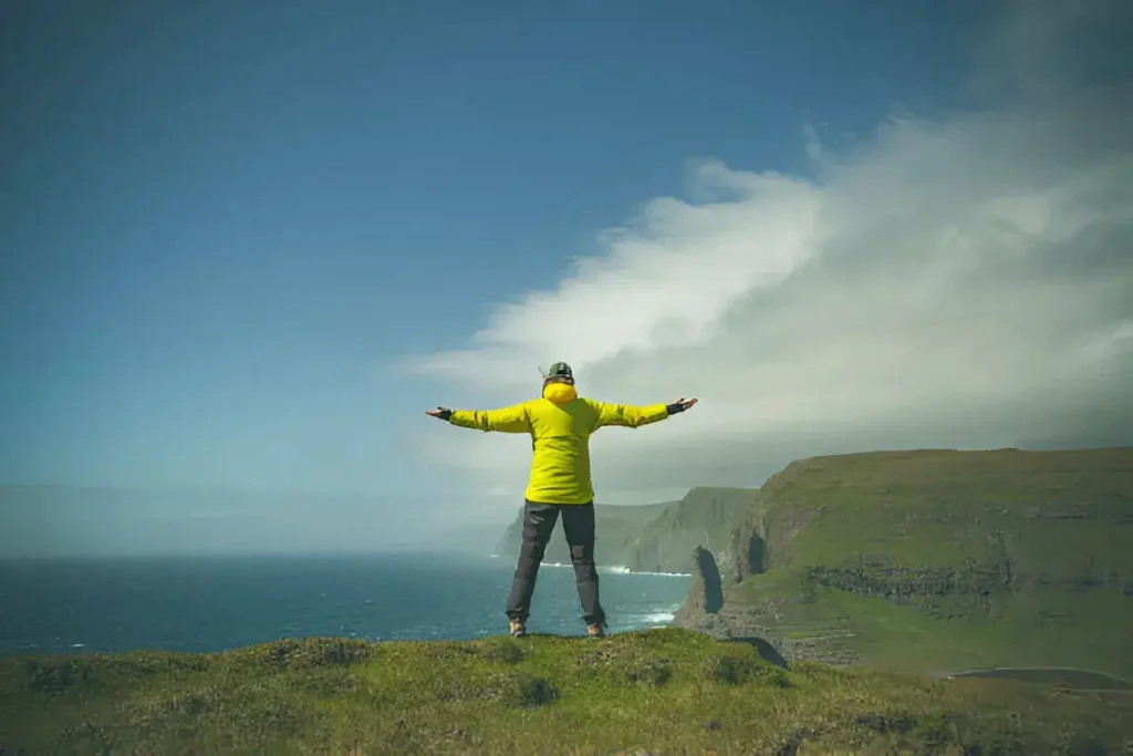 woman above sorvagsvatn lake at trælanípa a perpendicular rock wall, which just 142 meters upwards out of the sea, next to the fresh water lake sørvágsvatnleitisvatn which floats above the ocean and is the largest in the faroe islands